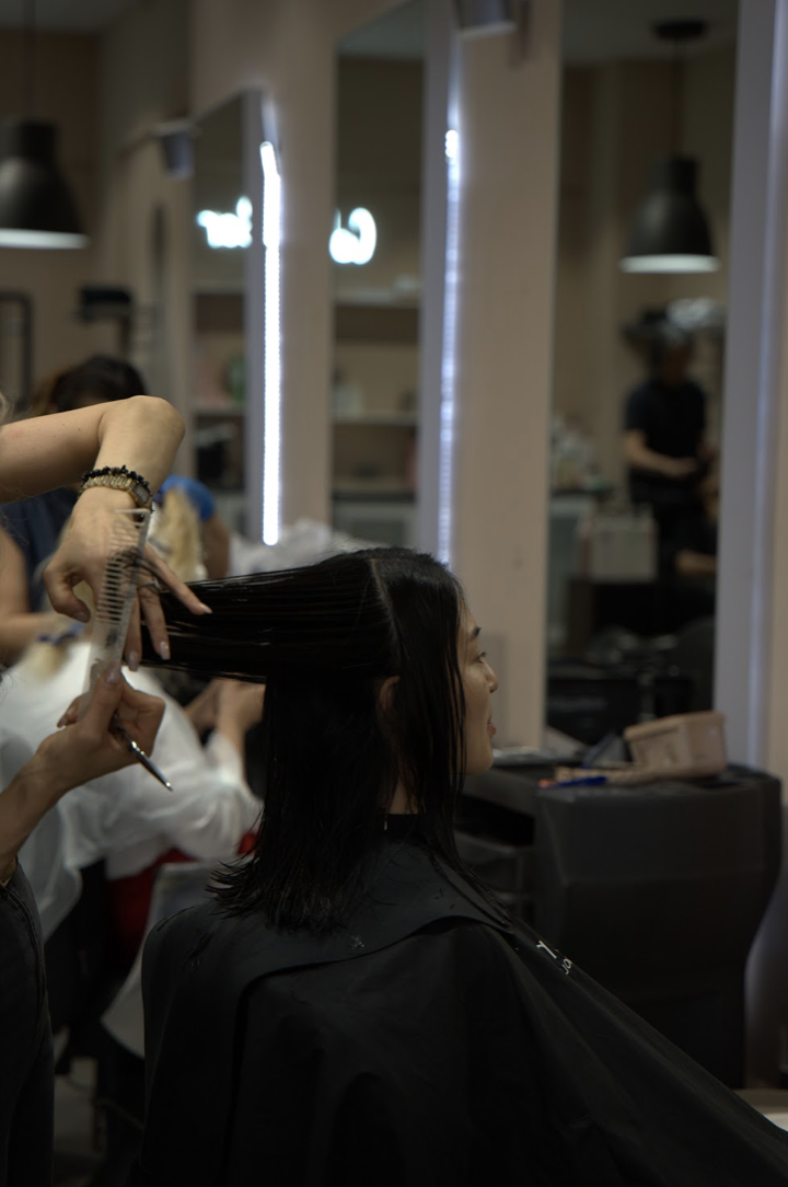 A stylist combing and cutting a client's hair